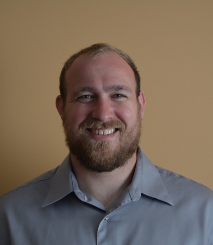 portrait of Brian Haas, a ruddy light-skinned person with short blonde hair and beard wearing a grey collared shirt