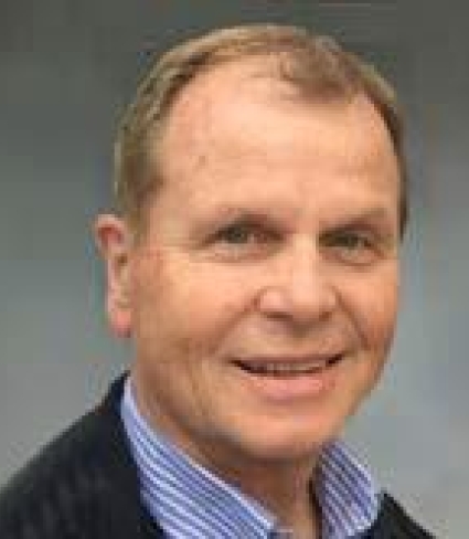 portrait of Daniel Molloy, a light-skinned person with short light-brown hair wearing a blue and white striped collared shirt and a black sweater