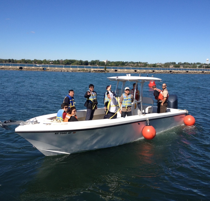 A group of people on a boat in a river wave as they approach the dock