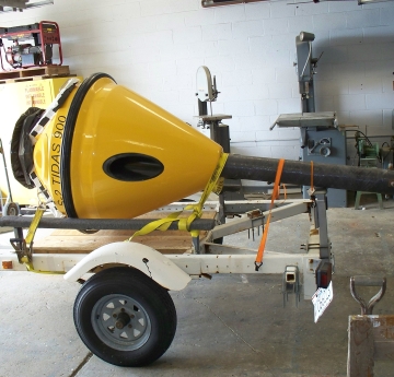 The body of a fiberglass buoy sits on a trailer in a garage