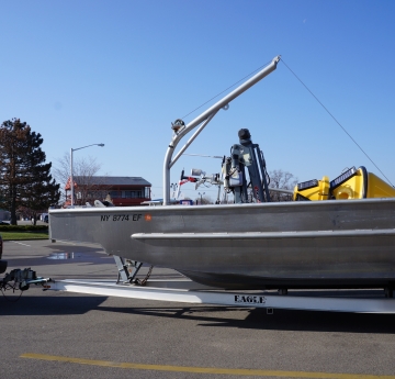 A boat with a buoy lying on it, on a trailer in a parking lot