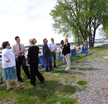 People standing outside by the waterfront. There is an experiment trough set up behind them, and a boat on a trailer nearby.