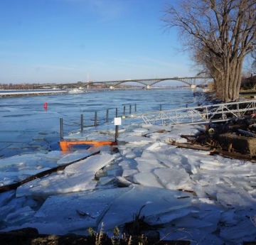 A boat dock and shoreline covered with broken sheets of ice.