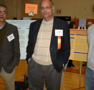 Three people pose for a picture in front of posters on easels