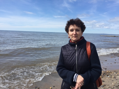 A person poses for a picture as waves wash on a beach behind them.