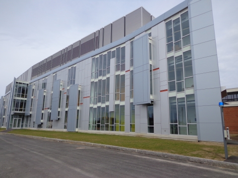 a three-story grey academic building with many windows