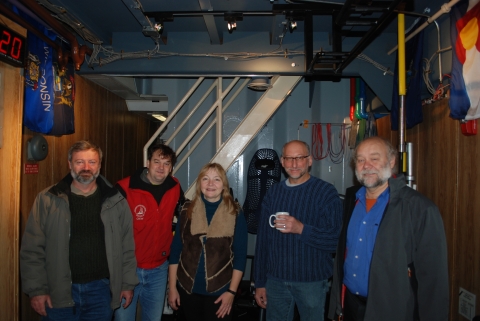 Five people pose together in a small room in a ship