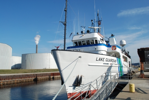 A large boat called Lake Guardian tied up at dock in a commercial slip.