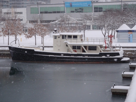 black and white boat docked in icy water in front of some buildings in a snowy city