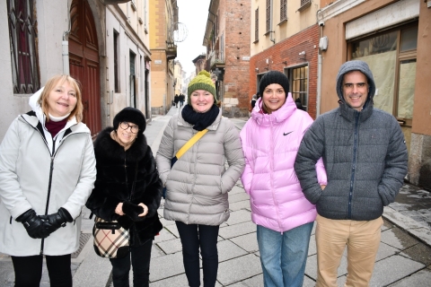 Five people in winter jackets stand in a narrow street between buildings in a city