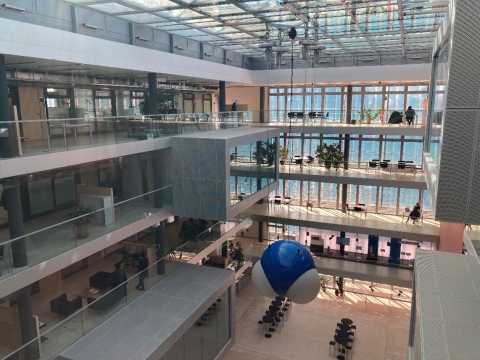The lobby of a multistory building with many windows. A sculpture of H2O hangs from the ceiling, a blue molecule between two smaller white molecules at 120º angle