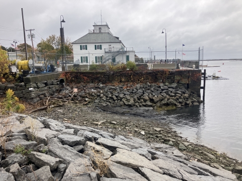 Low water level exposes mud, rocks, and debris in an inlet between two waterfront properties