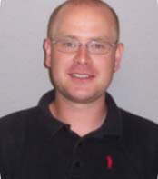 a person with very short hair and glasses wearing a dark polo