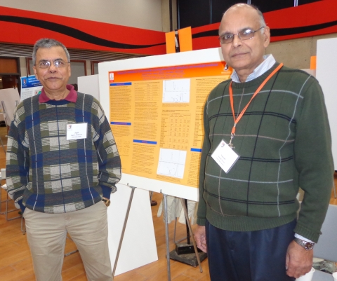 Two people standing in front of a poster on an easel.	