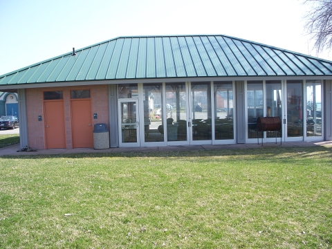 A small building with a green roof and floor-to-ceiling windows on three walls.