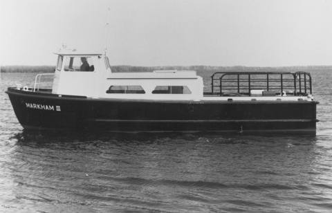 black and white photo of a small buoy tending boat with Markham III on its bow