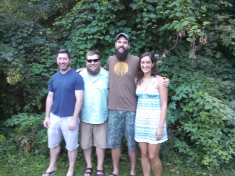Four people pose in front of foliage.