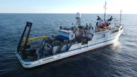 A ship on a large body of water. There are a few people on the back deck of the boat. The boat says "U.S. Environmental Protection Agency."