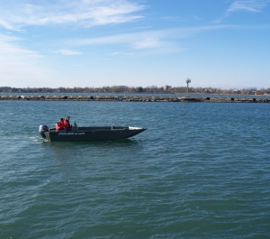 two people in cold water safety coats ride in an outboard motorboat labeled "Polarkraft"