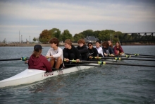 Eight teen rowers and a coxswain in a rowing scull on a canal