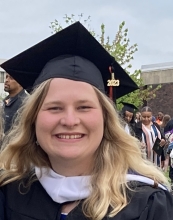 A smiling person in robes and a graduation cap with 2023 on the tassel