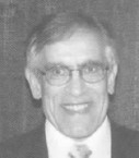 black and white portrait of a person with graying hair and glasses in a suit and tie