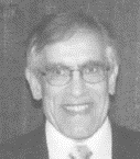 black and white portrait of a man with graying hair, with glasses, wearing a suit and tie