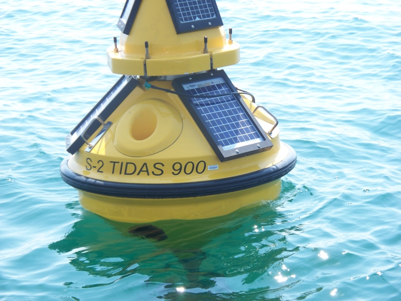 A fiberglass buoy with solar panels sits in the water, labeled "S-2 Tidas 900"