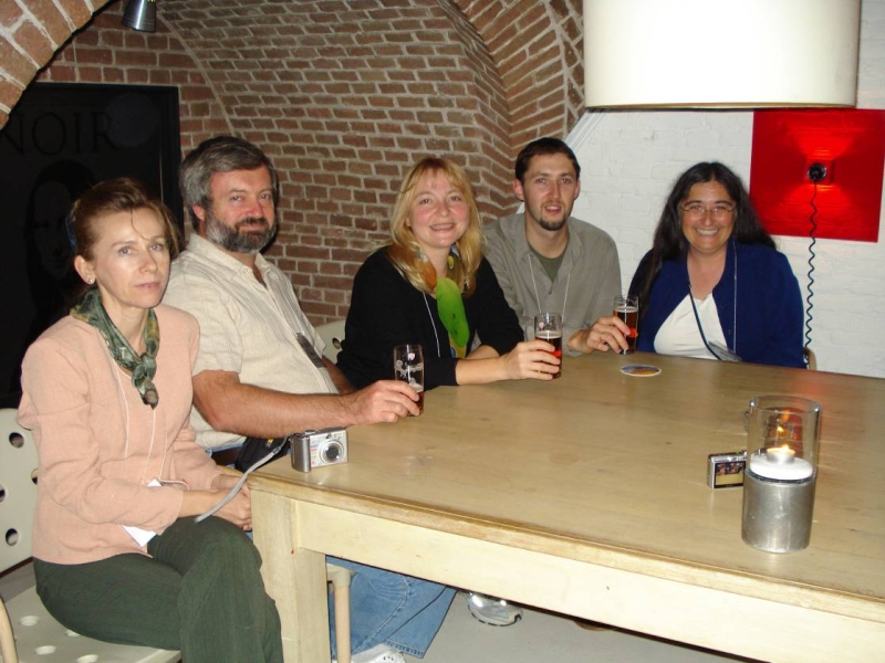 five people sit at a table with a large brick alcove behind them