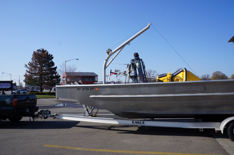 A boat with a buoy lying on it, on a trailer in a parking lot