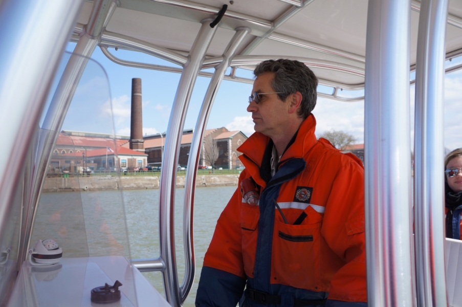 A person stands at the controls of a boat with a canopy