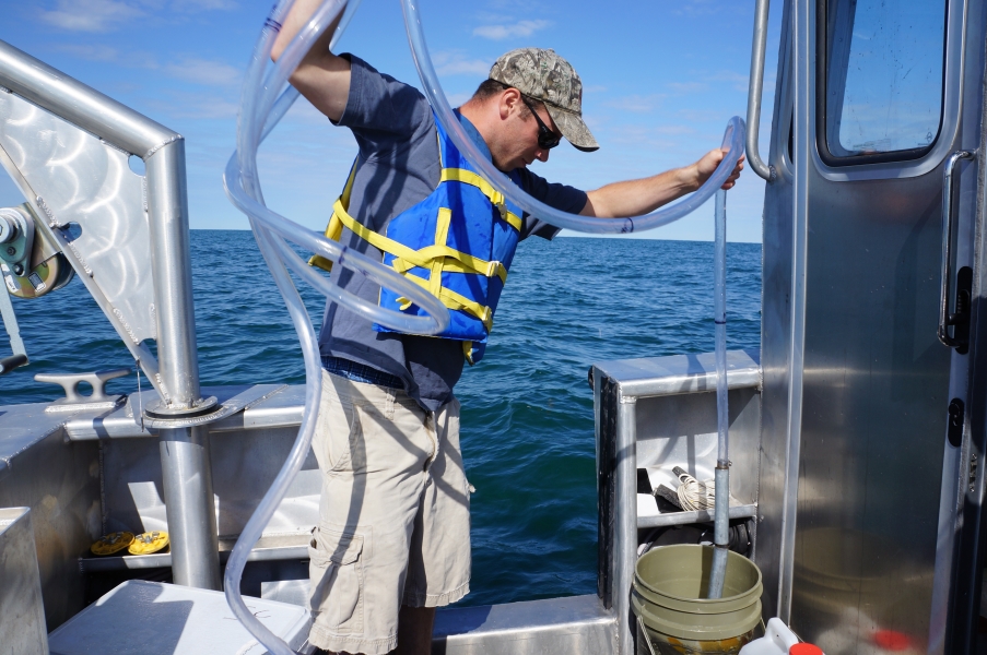 A person on a boat empties a long tube into a bucket