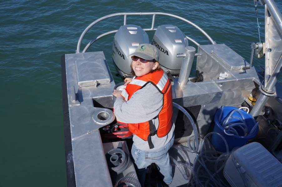 A person working on the back of a boat, smiling at the camera