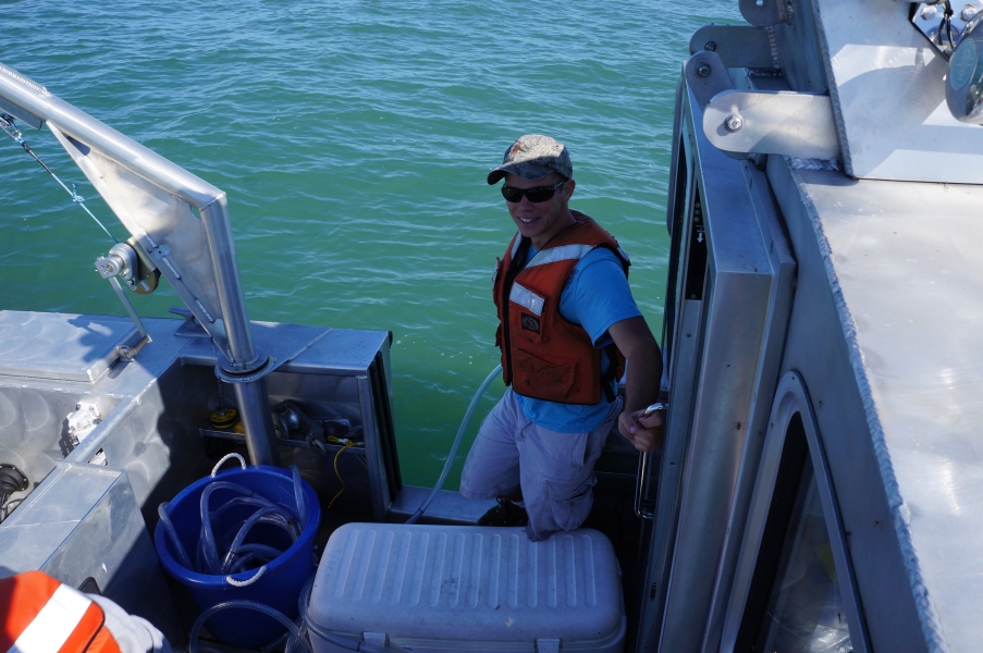 A person in the back of a boat holds a tube in the water