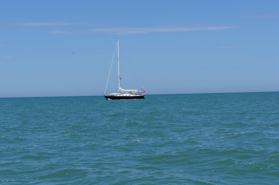 A sailbot sits on the water with its sails stowed