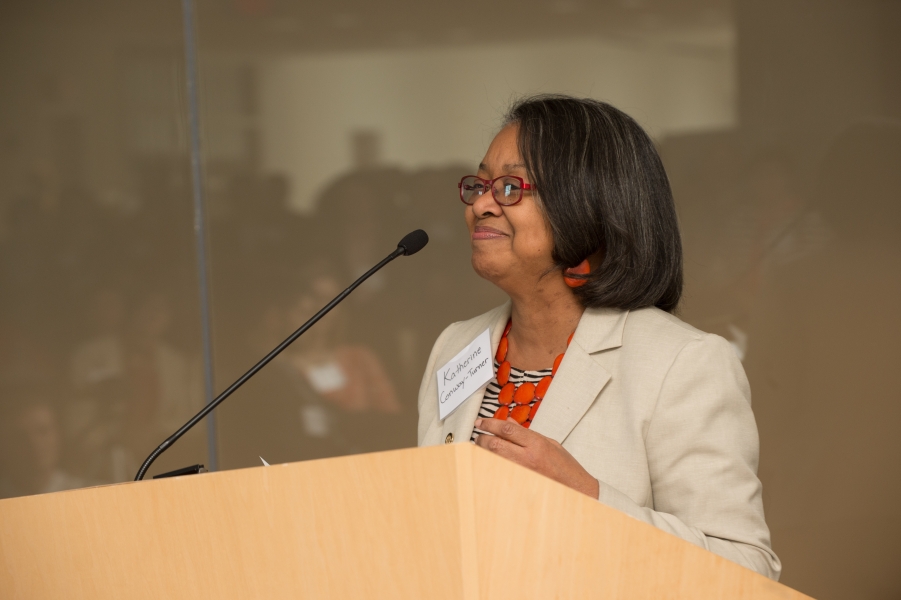 a person with name tag "Katherine Conway-Turner" smiling behind a podium