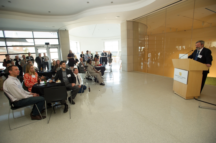 a person at a podium presents to seated and standing guests