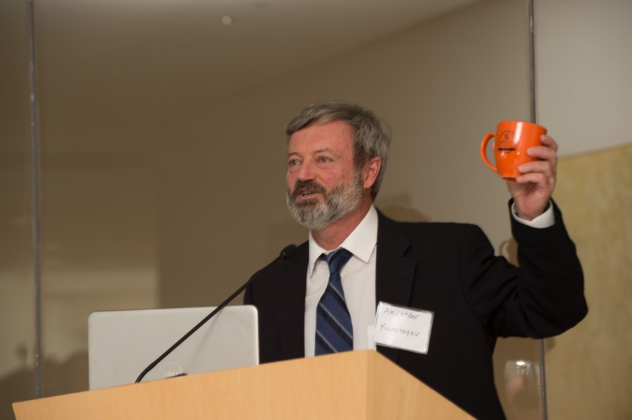 a person at a podium holds up a coffee mug with a logo