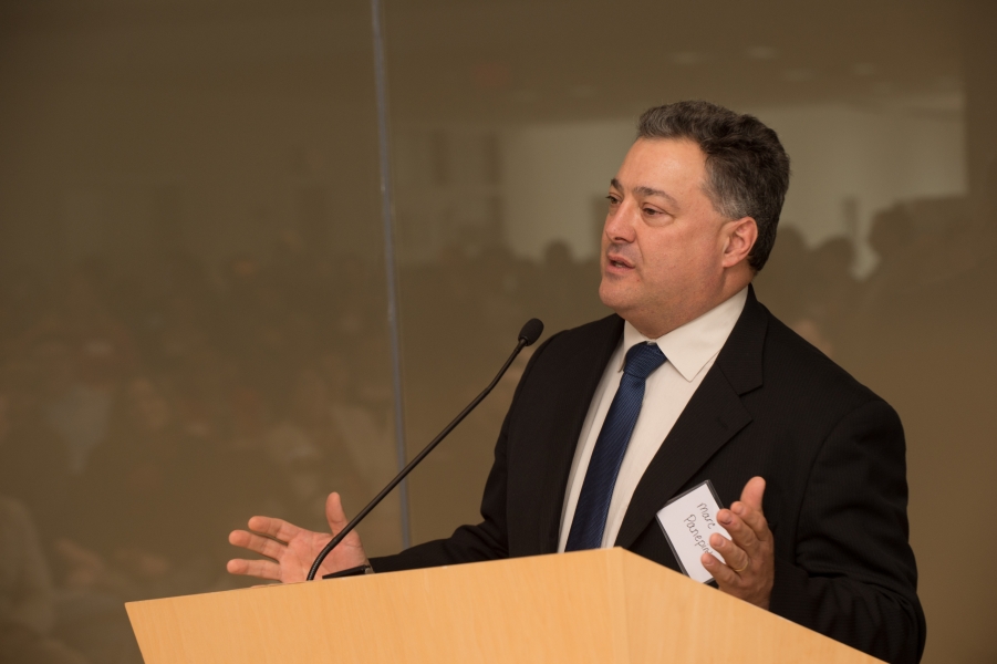 a person with name tag "Marc Panepinto" talking at a podium