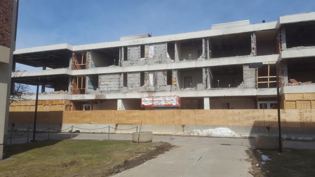 A construction site. The walls have been removed from this three-story academic building. Fences surround the building.