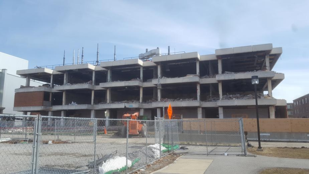 A construction site. The walls have been removed from this three-story academic building. Fences surround the building.