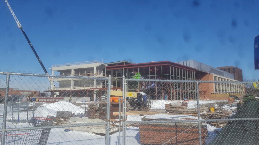 A building under construction. Part of the building is constructed of concrete while the other part is mainly steel beams.