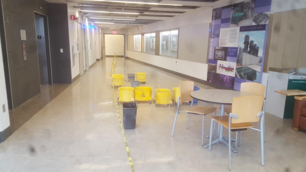 A hallway with many buckets in it to catch leaks.