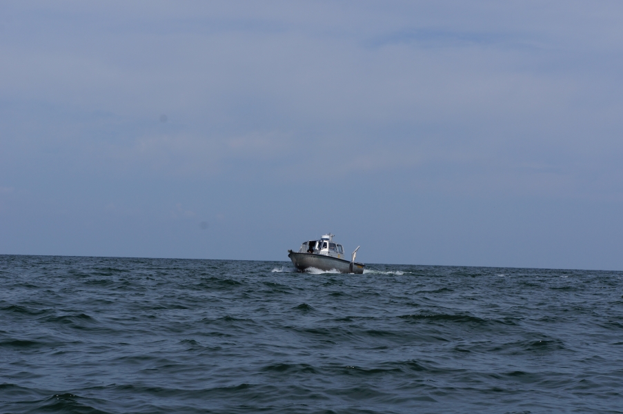 A metal boat with a cabin cruising on a large body of water