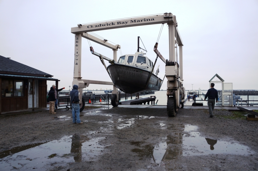 A large metal frame with straps holding up a boat near the marina