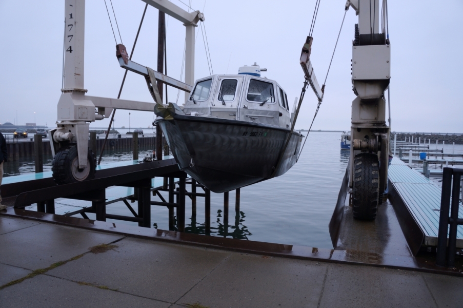 A metal frame holding a boat on straps over the water