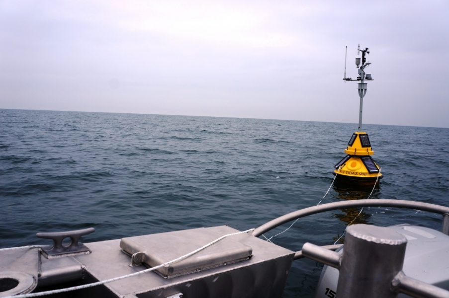 A science buoy seen from the back of the boat. There are ropes going from the buoy to the boat.