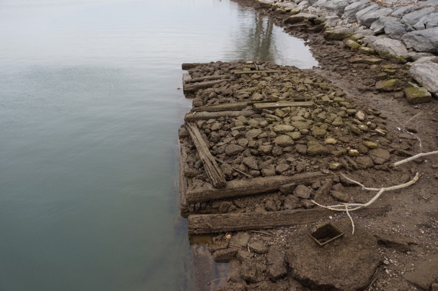 The entire shape of algae-covered stone and wood cribbing is visible above the water.