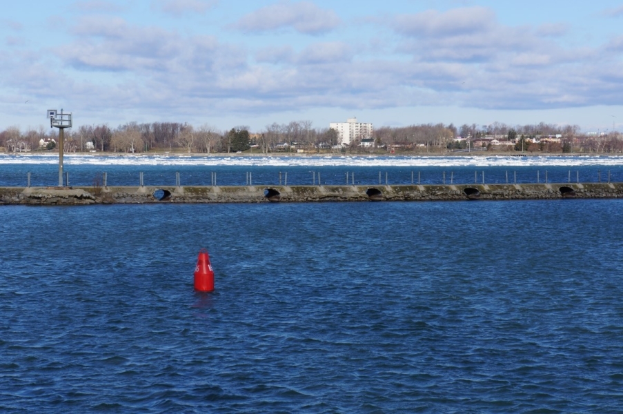 Two bodies of water separated by a stone pier. On the far side, there is ice in the water. The near side is clear.