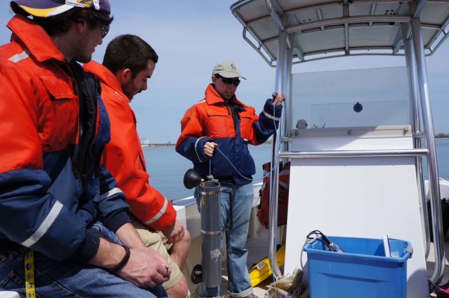 Two people look on as a third person holds up a plastic tube on a thin rope